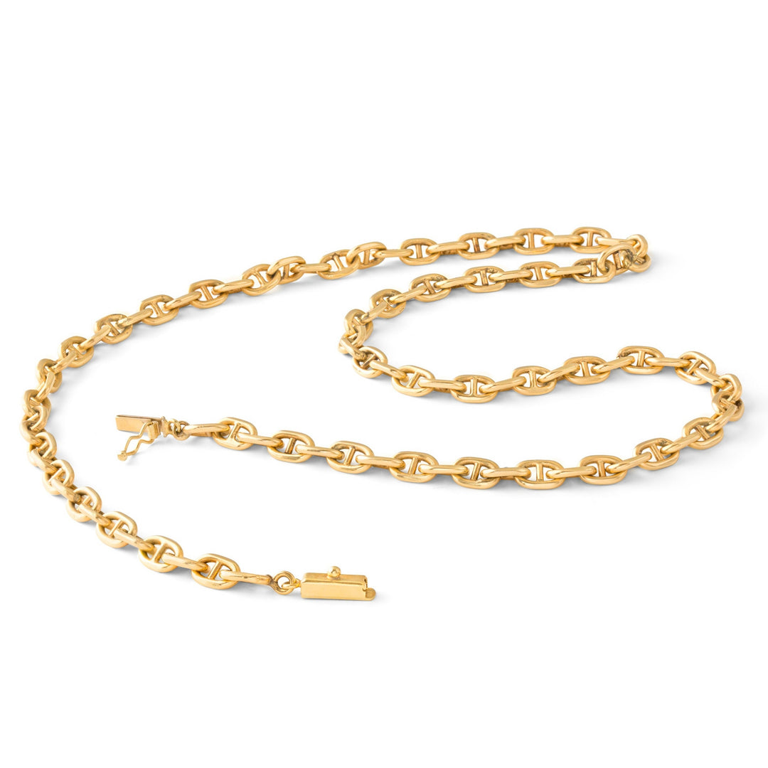 Create a detailed image of a vintage mariner chain necklace displayed on a classic wooden jewelry stand with a velvet backing. The necklace features intricate, aged gold links with a slight tarnish