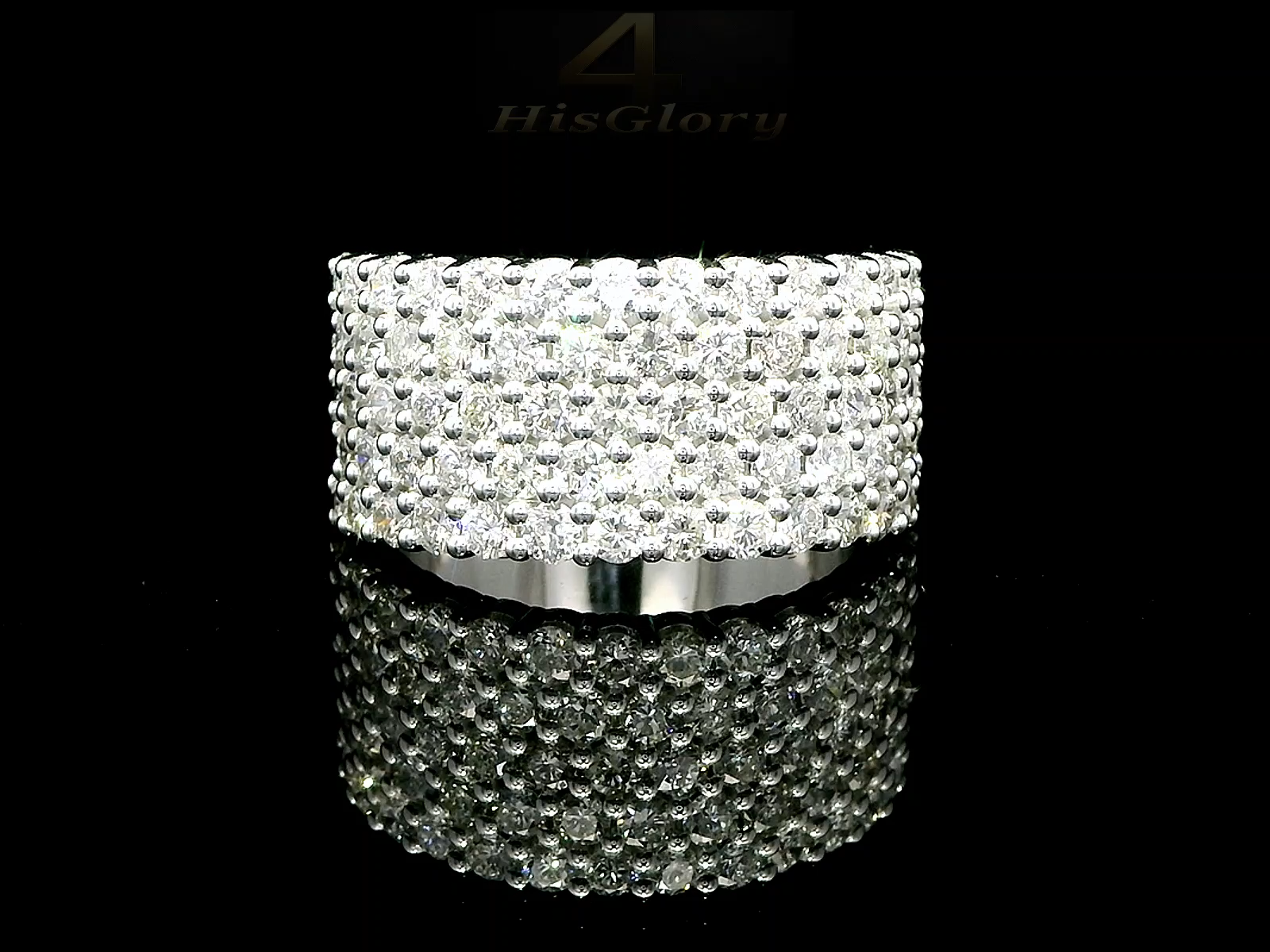 Close-up image of a white gold ring encrusted with multiple small diamonds, reflecting light on a black surface. The ring features a pattern of closely set diamonds creating a sparkling effect.