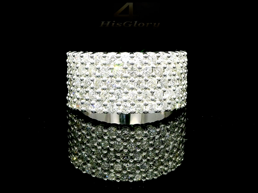 Close-up image of a white gold ring encrusted with multiple small diamonds, reflecting light on a black surface. The ring features a pattern of closely set diamonds creating a sparkling effect.