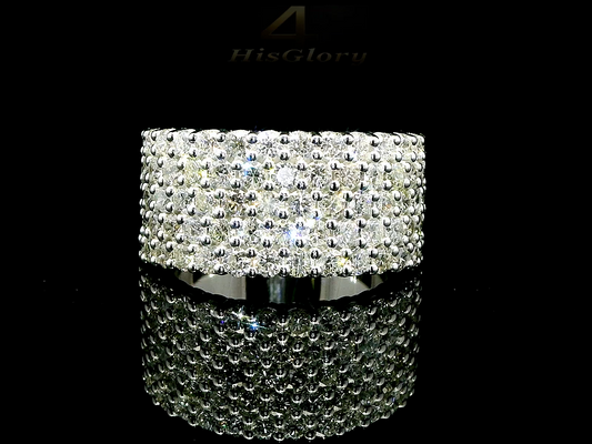 Close-up image of a white gold ring encrusted with multiple small diamonds, reflecting light on a black surface. The ring features a pattern of closely set diamonds creating a sparkling effect.